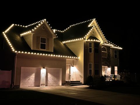 Warm white C9 lights on every roofline and gable on a two-story home with a two-car garage in Cary, NC